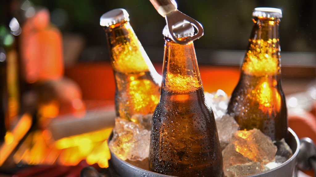Cold craft beer bottles in an ice bucket being opened at a fall backyard party, highlighting seasonal beer selections at Bullfrog Wine & Spirits in Fort Collins.