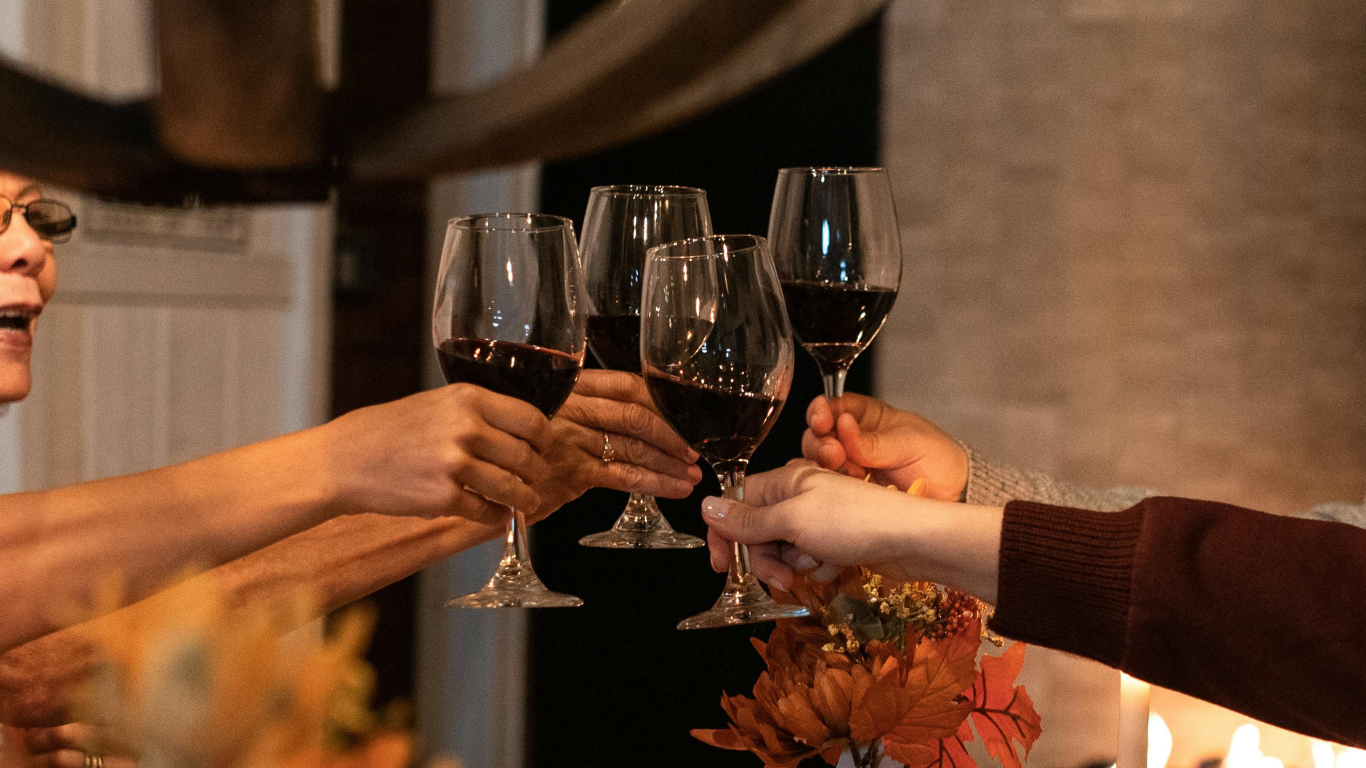 Group toasting with red wine at a festive Thanksgiving gathering. Celebrate the season with wine tastings at Bullfrog.
