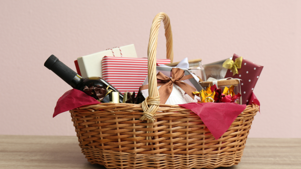 Festive holiday gift basket filled with a bottle of wine, wrapped presents, and gourmet treats, arranged in a woven wicker basket with red tissue paper, ideal for holiday or hostess gift ideas.